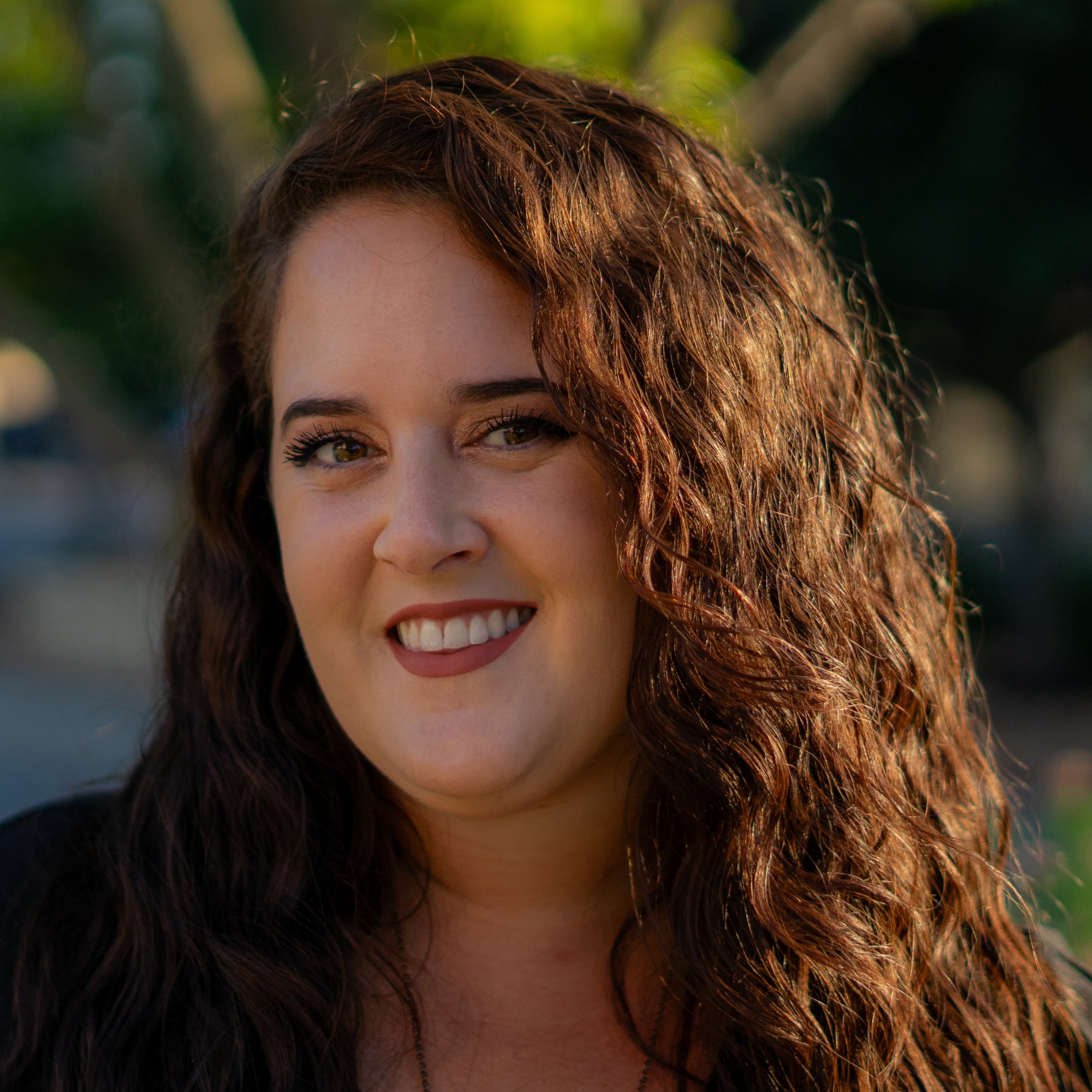 front office danielle Smiling woman with curly hair outdoors.